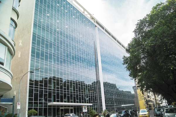 Edifício comercial com fachada de vidro espelhado após retrofit, em rua arborizada