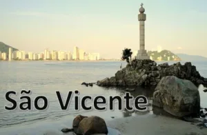 Orla de São Vicente com monumento sobre as pedras e prédios ao fundo