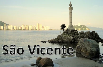Orla de São Vicente com monumento sobre as pedras e prédios ao fundo