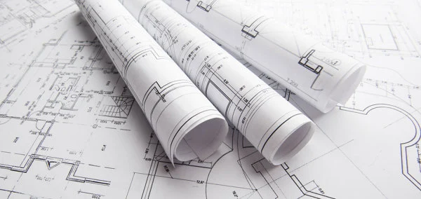 Plantas de projeto arquitetônico enroladas sobre desenhos técnicos de reforma