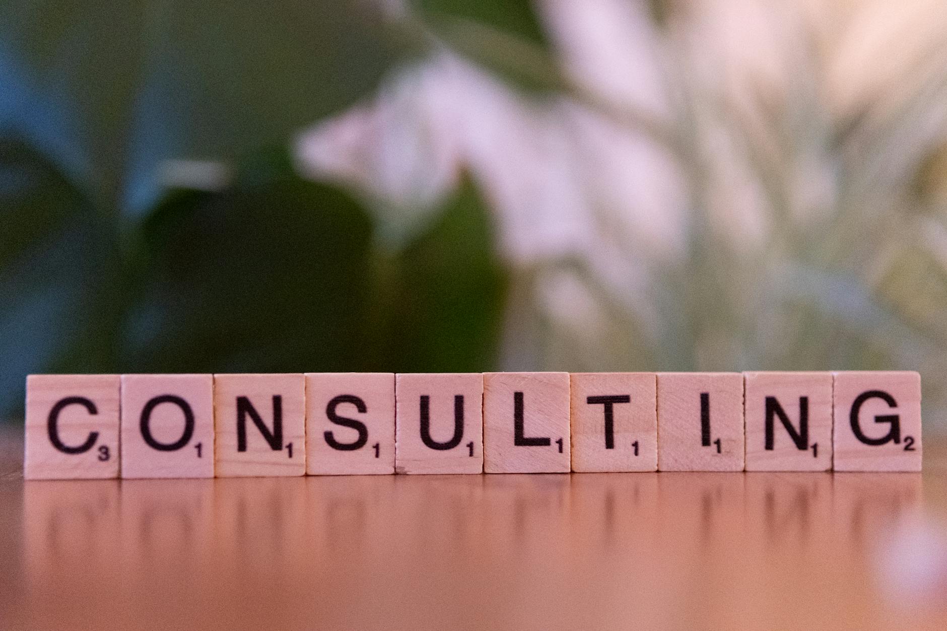 Peças de letras formando a palavra consultoria em inglês sobre mesa